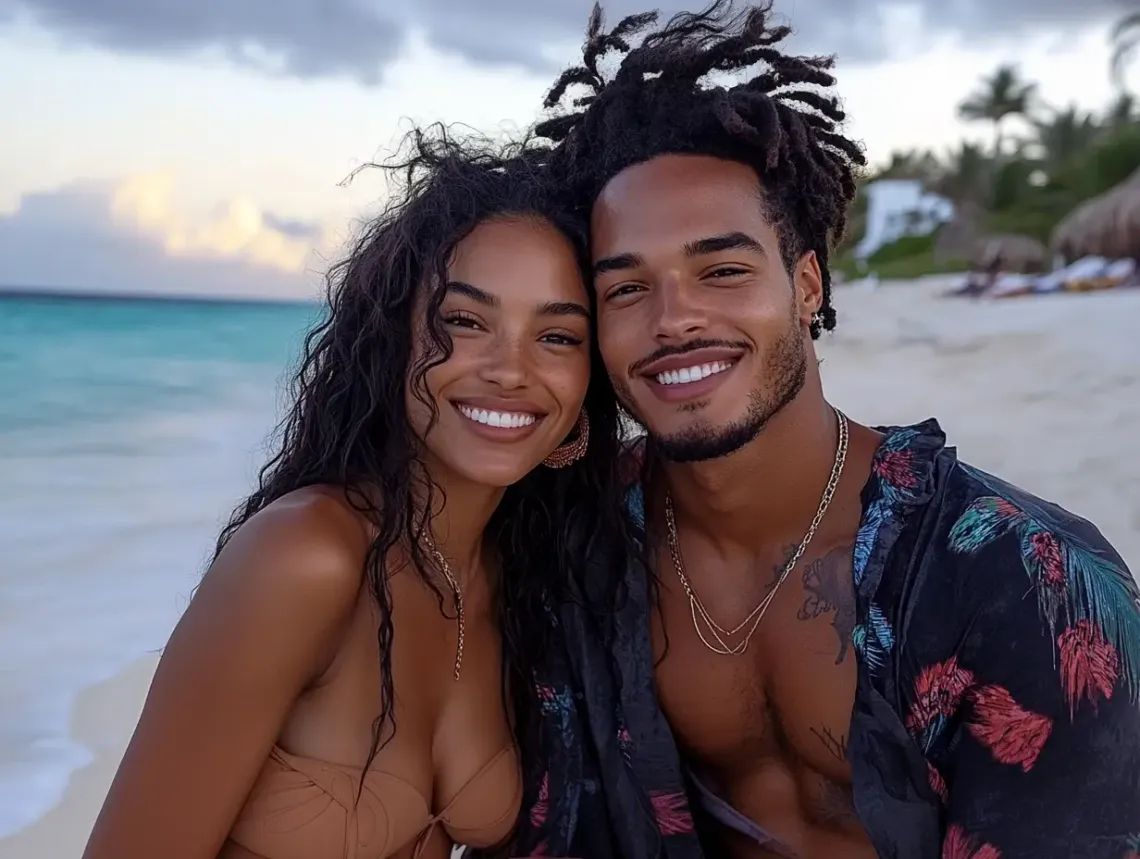 Happy couple posing on a sandy beach, man in casual clothes, woman in swimsuit, under a bright sun with clear sea backdrop.