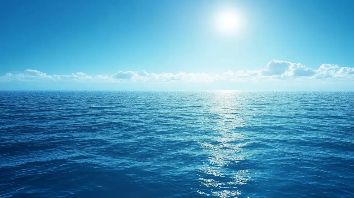 Bright sun shining over a calm, sparkling blue ocean under a clear and vibrant sky.